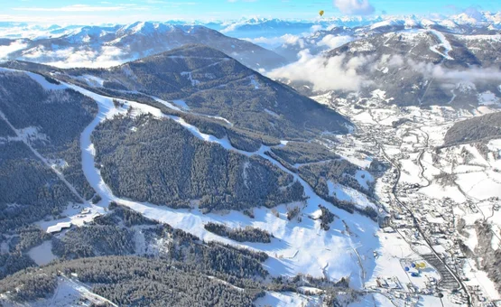 Snowy Alps with ski slopes and villages in the valley under clear sky