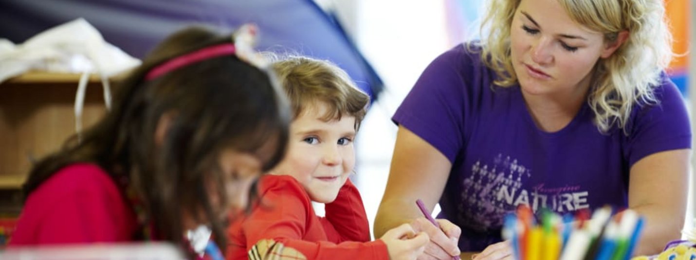 Frau und zwei Kinder malen gemeinsam an einem Tisch