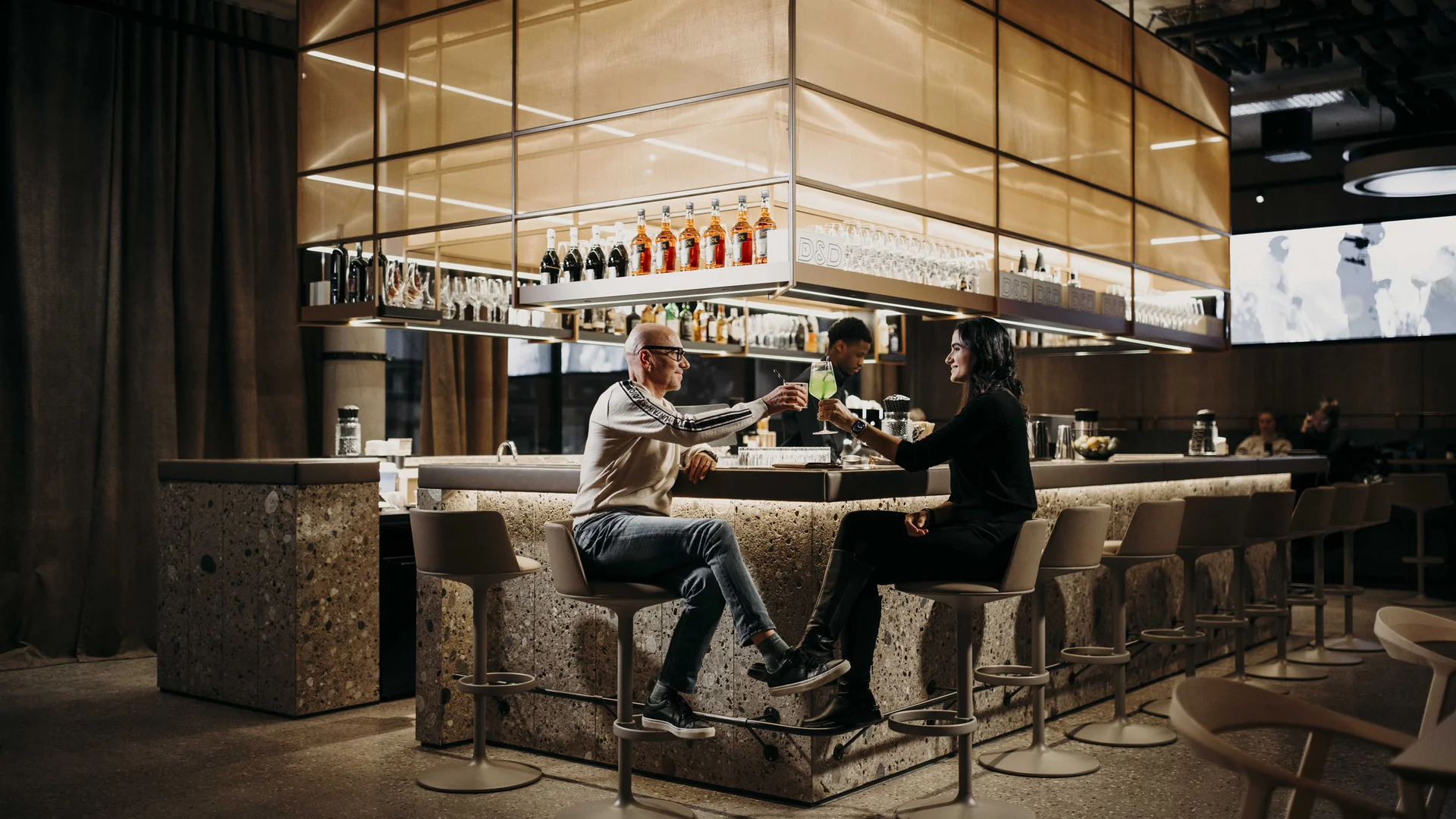 Zwei Personen stoßen mit Getränken an einer modernen Hotelbar an