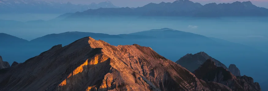 Sonnenuntergang beleuchtet Berggipfel mit nebelverhüllten Bergen im Hintergrund