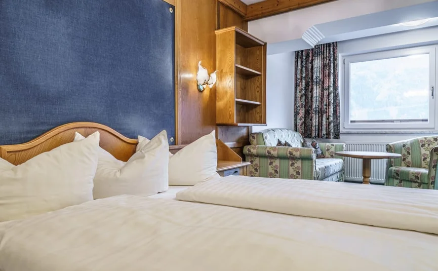 Cozy hotel room with double bed, armchairs, and window with curtains