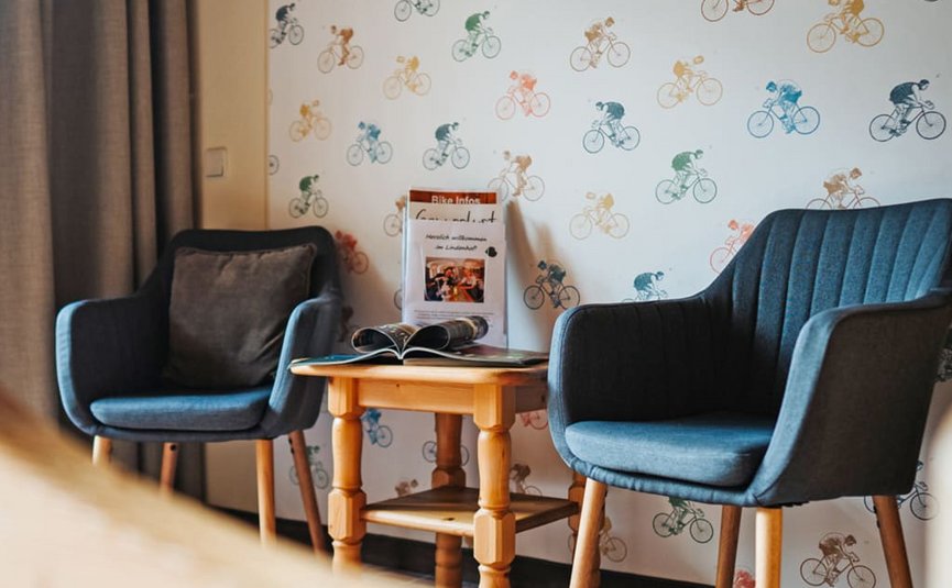 Ladylike Radmarathon Package - 2 nights Two blue armchairs and a wooden table in front of a wall with bicycle pattern