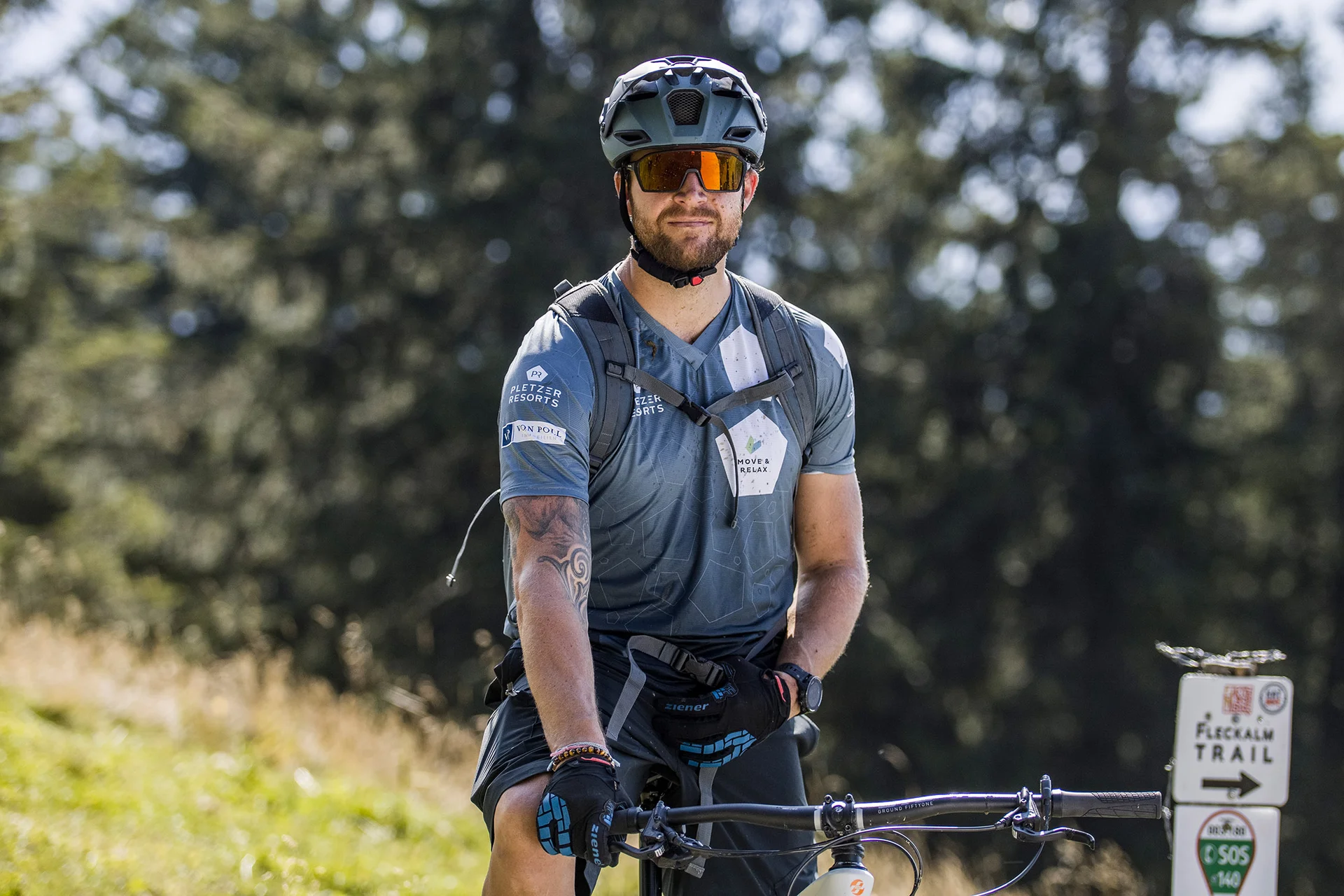 Mann mit Fahrradhelm auf Mountainbike-Trail mit Wegweiser im Hintergrund
