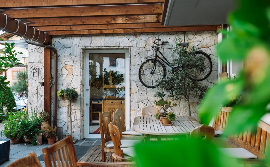 Hotel Innerhofer *** © Neubaua Gemütliche Terrasse mit Holzmöbeln und Fahrrad an Steinwand