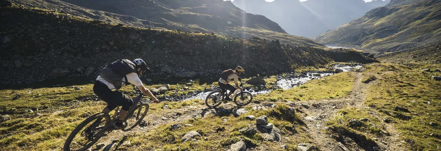 Two mountain bikers riding on a sunny mountain trail