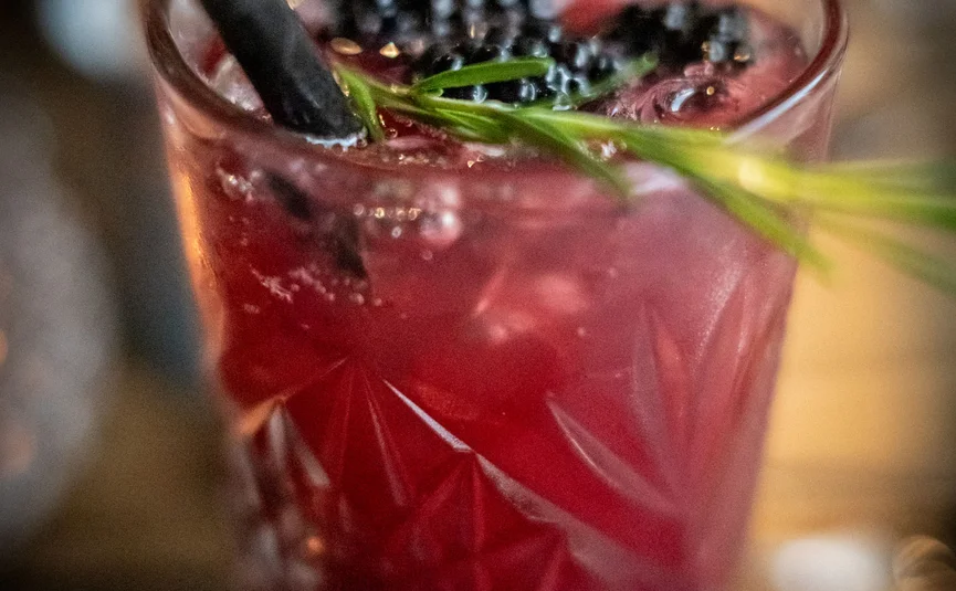 Roter Cocktail mit Brombeeren, Rosmarin und schwarzem Trinkhalm