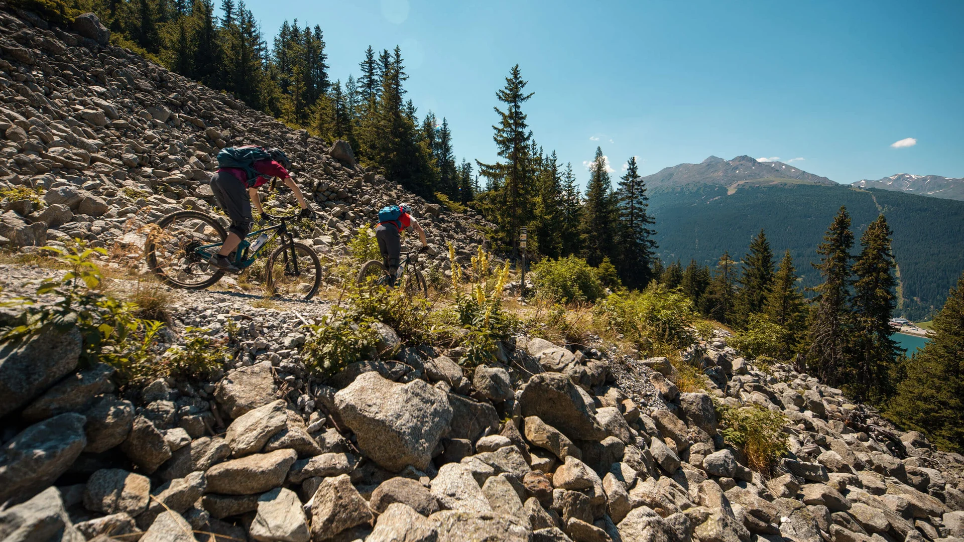 Zwei Mountainbiker fahren auf felsigem Bergpfad bei sonnigem Wetter