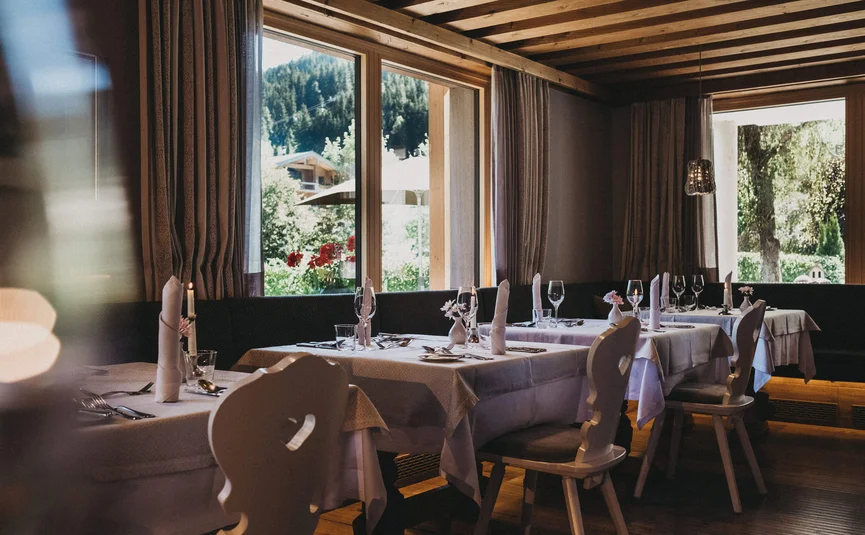 Gemütliches Restaurant mit gedeckten Tischen und Bergblick durch Fenster
