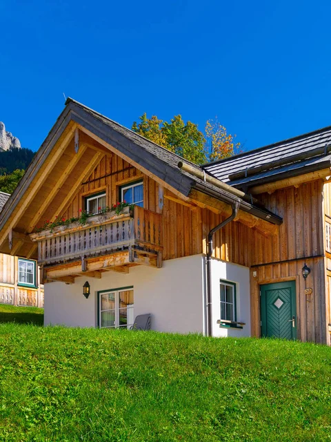 Holzhäuser im grünen Tal mit Berg und blauem Himmel im Hintergrund