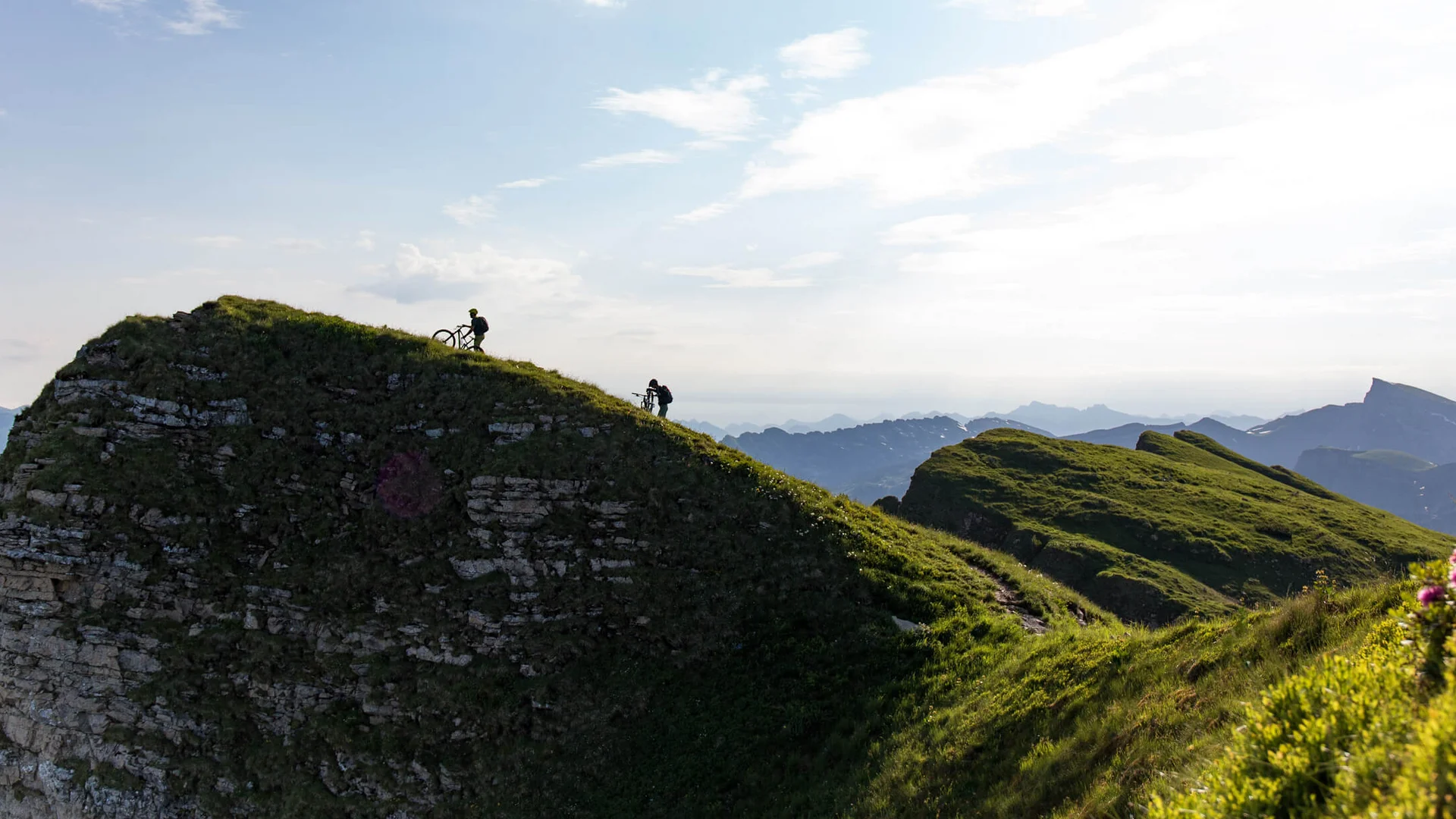 Twee fietsers duwen fietsen een met gras bedekte heuvel op in berglandschap