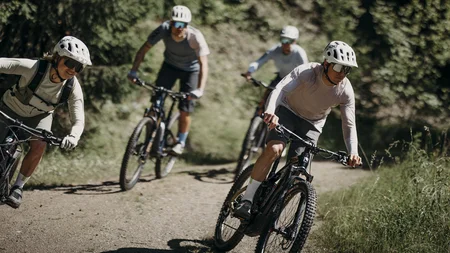 Vier Radfahrer fahren auf einem Waldweg bergab