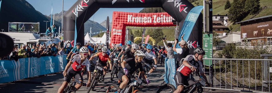 Mountainbike-Rennen mit Fahrern bei Start unter Ischgl-Bogen