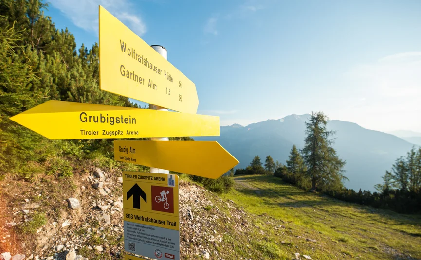 Yellow hiking trail signs in Tirol Zugspitz Arena with mountain view