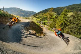 Flow Trail Special / 3 nights Two mountain bikers riding on a winding mountain trail on a sunny day