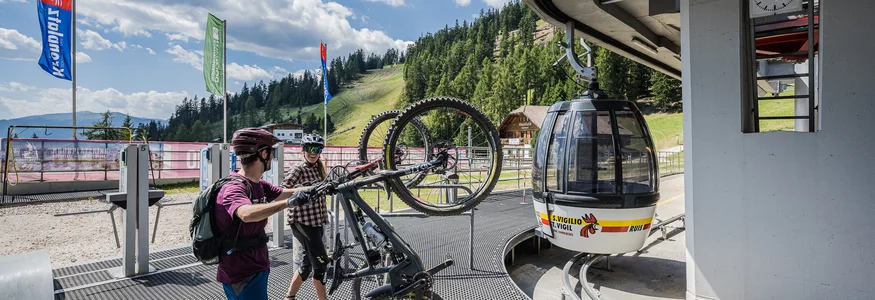 Bikeurlaub per Bahn © Harald Wisthaler Zwei Radfahrer heben Mountainbikes zur Gondelstation in einer Berglandschaft