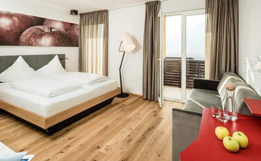 Modern hotel room with double bed, sofa, and balcony with view