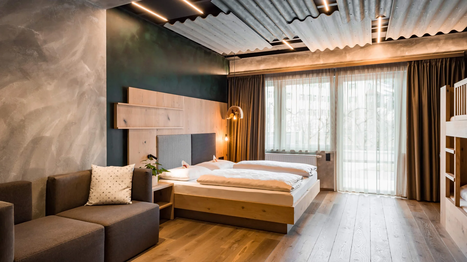 Modernes Schlafzimmer mit Holzbetten, Sofa und großen Fenstern mit Vorhängen