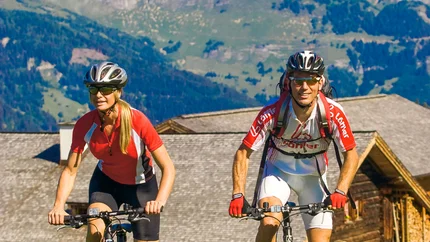 Mann und Frau fahren Mountainbike auf grünem Feld in den Bergen