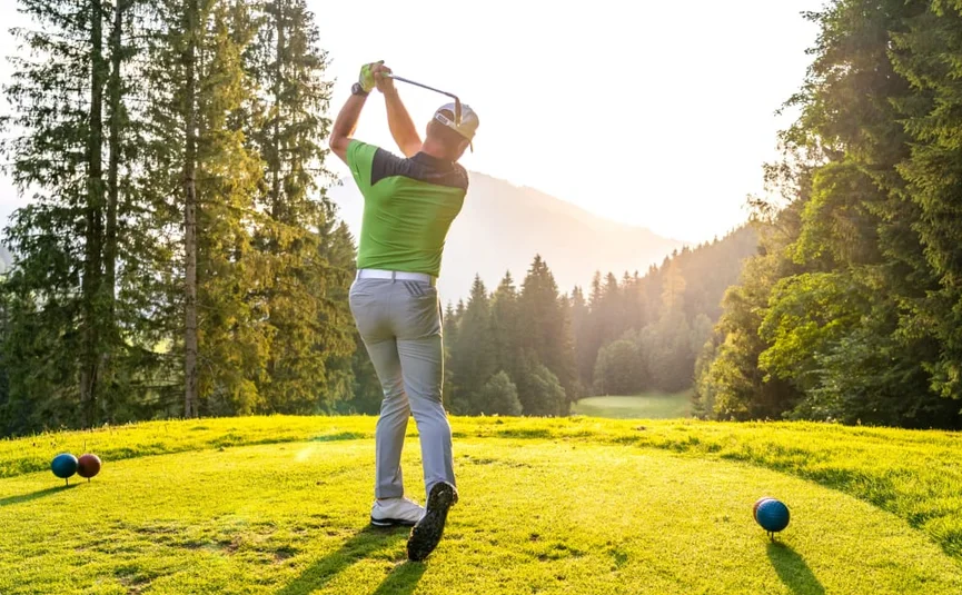 Golf Unlimited 4 days Golfer hitting ball on sunny golf course with forest and mountains behind