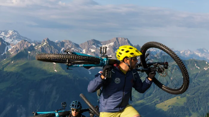 Zwei Mountainbiker tragen ihre Fahrräder in den Bergen