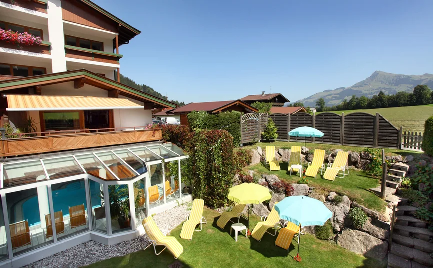 Hotelgarten mit Liegestühlen und Sonnenschirmen bei Bergkulisse