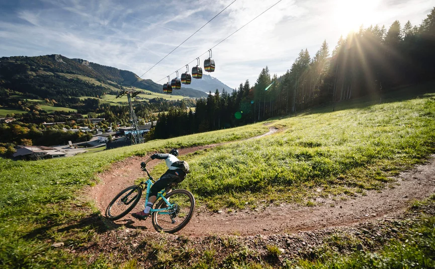 Mountain biker rides on winding trail in sunny mountain landscape
