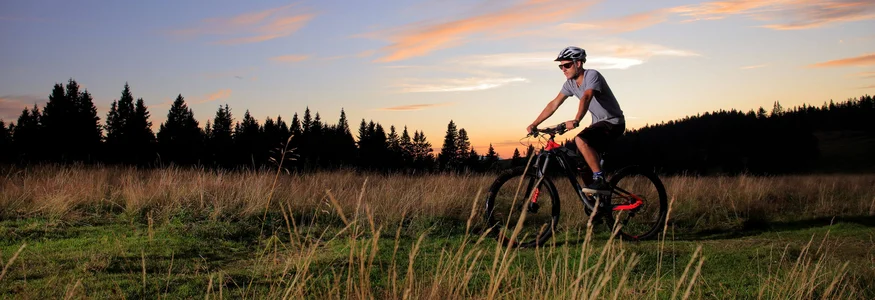 Mountainbike Urlaub in Rogla – Pohorje © Dan Briski Mann fährt Mountainbike auf Wiese bei Sonnenuntergang