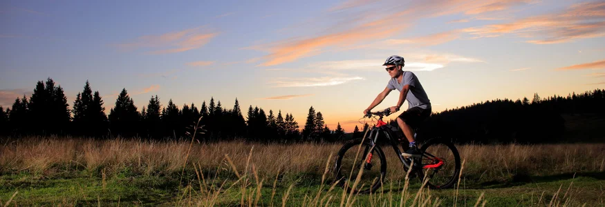 Man mountainbiken op grasveld bij zonsondergang
