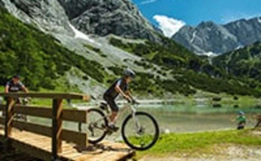 Child jumps with mountain bike off wooden bridge in mountainous area