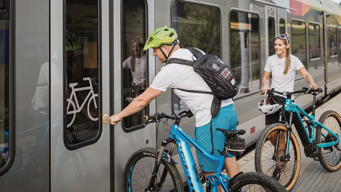 Personen mit Fahrrädern warten auf Zug mit Fahrradabteil