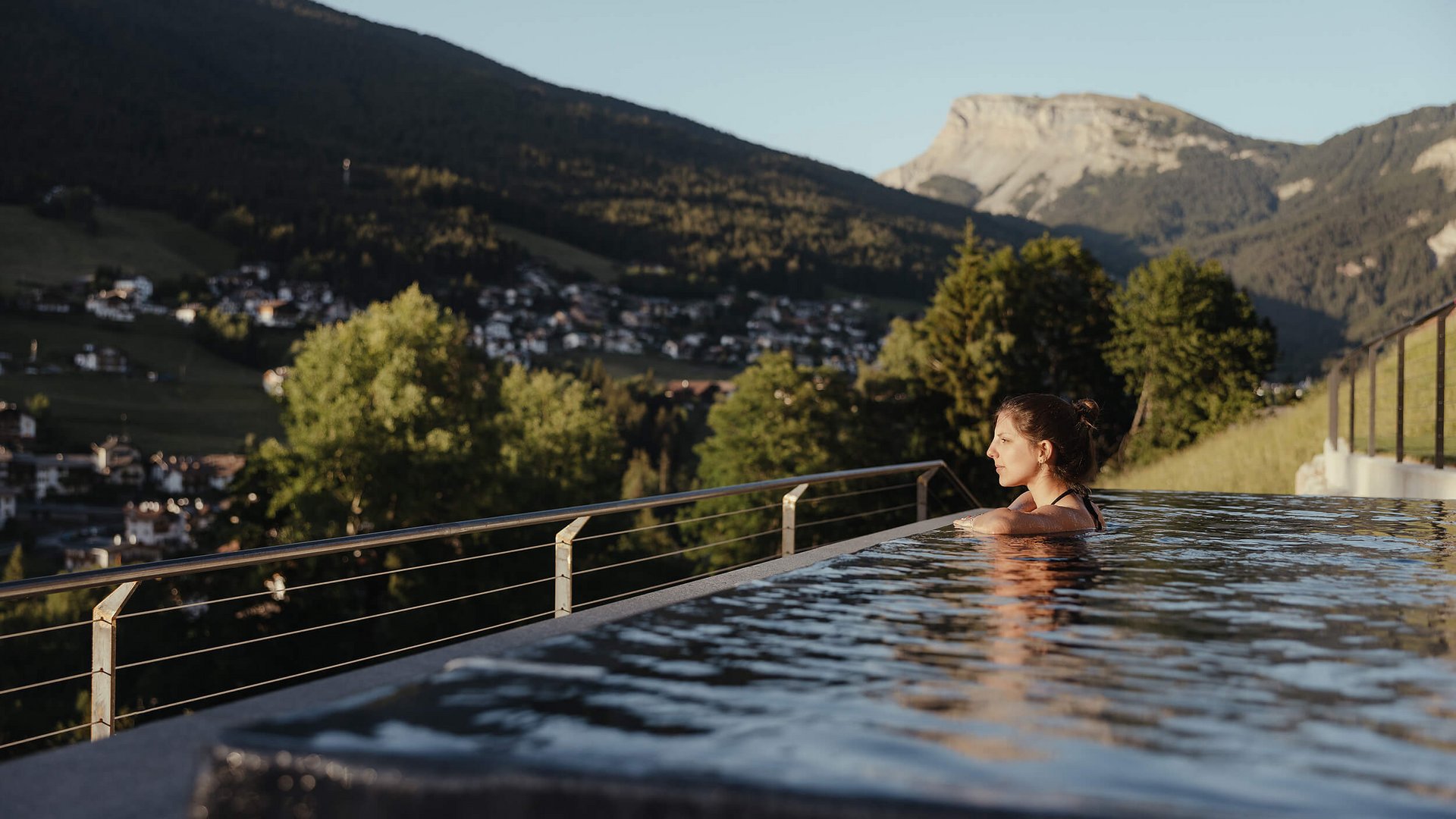 Frau entspannt im Infinity-Pool mit Blick auf Berge und Tal