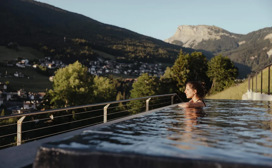 Vrouw ontspant in infinity pool met uitzicht op bergen en dal