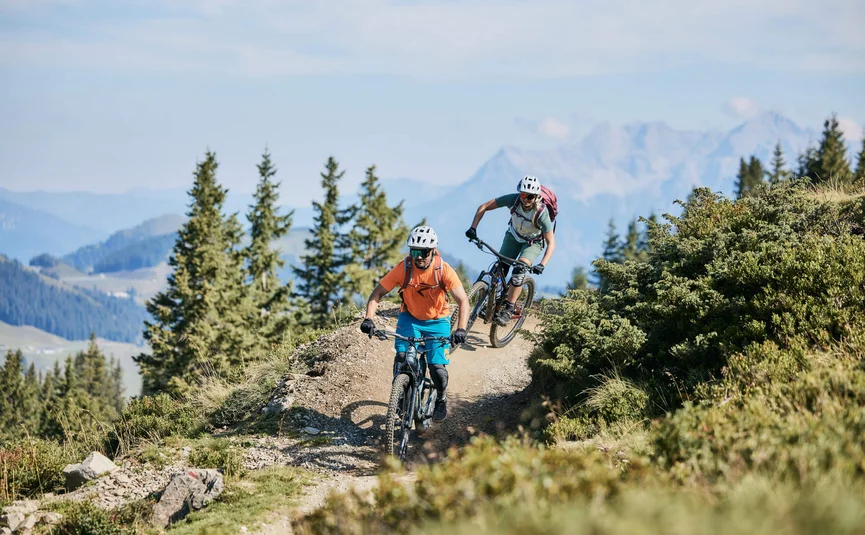 Two mountain bikers riding on a mountain trail on a sunny day