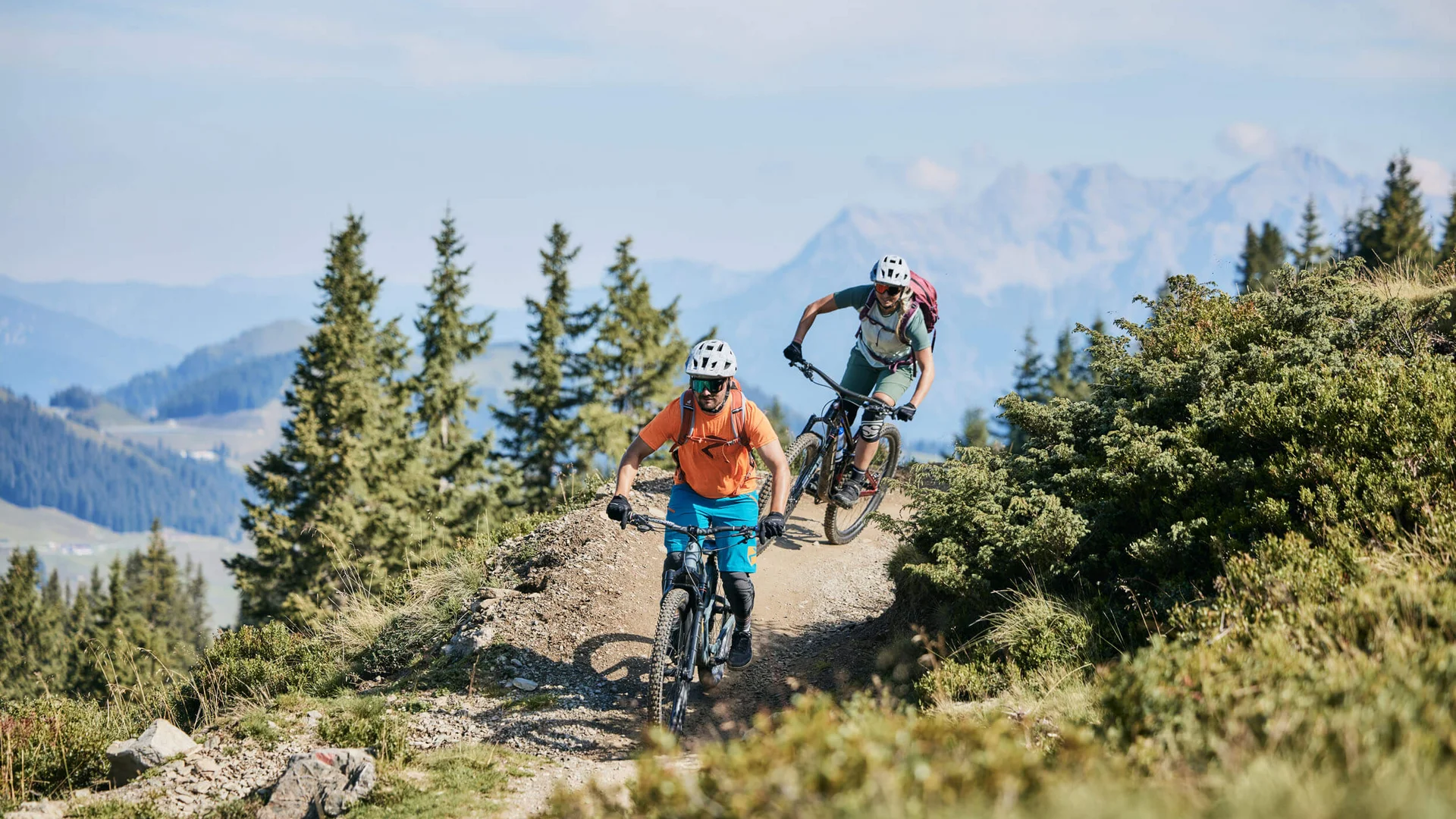 Zwei Mountainbiker fahren auf einem Gebirgspfad bei sonnigem Wetter