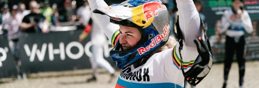 Mountainbiker feiert mit Helme am Rennort mit Zuschauern im Hintergrund