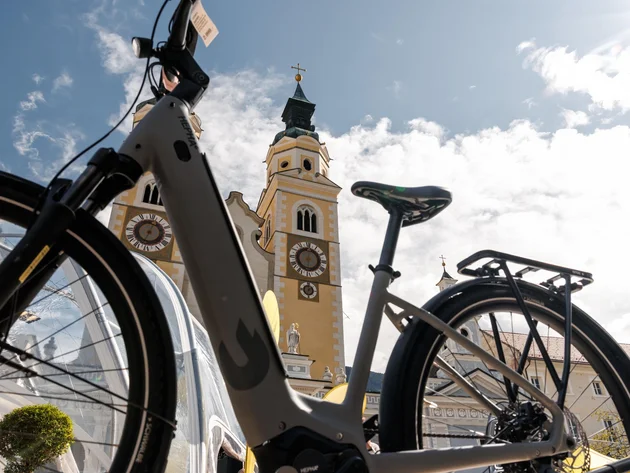 Das war die bike festa Südtirol in Brixen © Brixen Tourismus - Bike vor dem Dom Brixen Fahrrad vor einem gelb-weißen Kirchturm mit Zifferblättern unter blauem Himmel