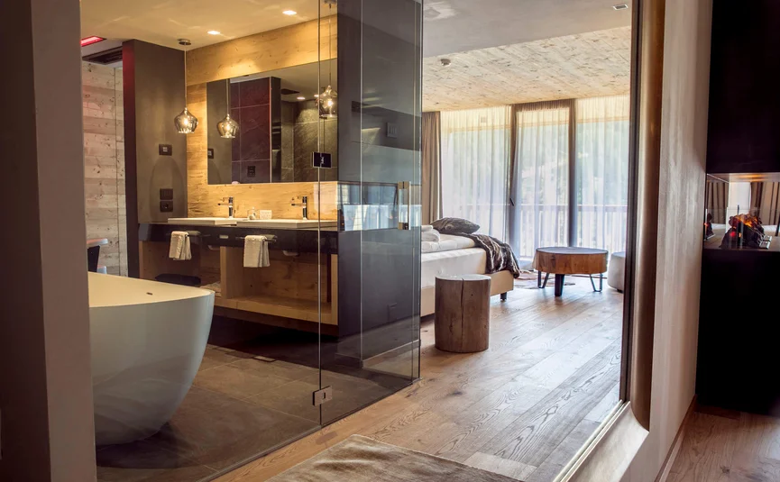 Modern hotel room with bathtub, double sinks, and balcony