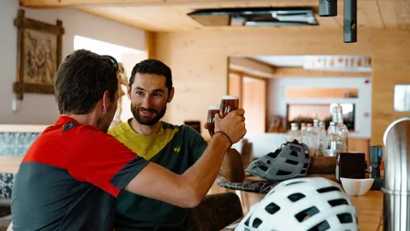 Zwei Männer stoßen mit Biergläsern in einer Bar an