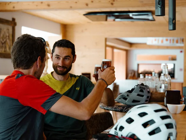 Zwei Männer stoßen mit Biergläsern in einer Bar an