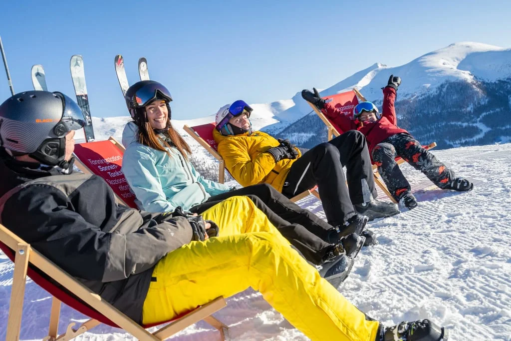Easter Bunny Fun includes ski pass - 5 nights Four people in ski gear sit on sled chairs in snowy mountains