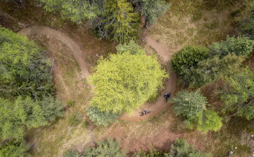 Zwei Mountainbiker fahren auf kurvigem Waldweg aus der Vogelperspektive