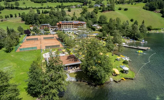 Happy Family week Aerial view of hotel, tennis courts, and lake in green countryside
