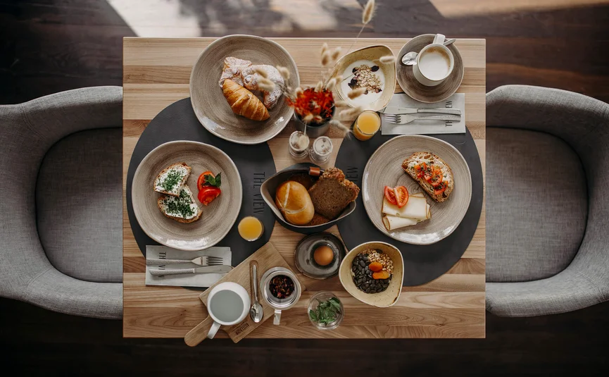 Breakfast with bread, croissant, cheese, tea, and orange juice on wooden table