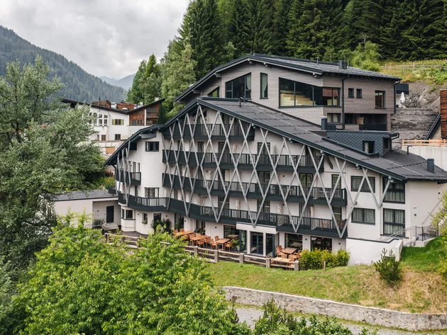 Modernes Hotel in den Bergen umgeben von Bäumen und Wolken