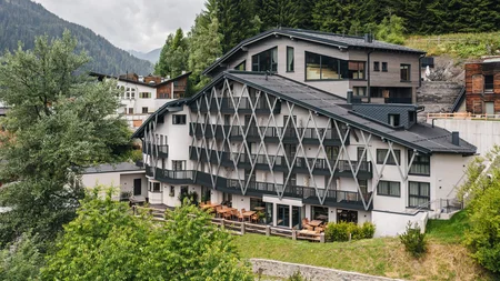 Modernes Hotel in den Bergen umgeben von Bäumen und Wolken