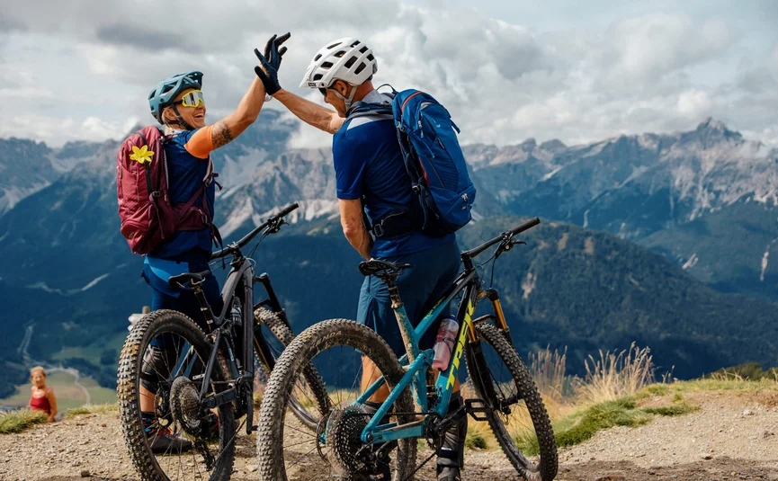 Two mountain bikers high-fiving on a mountain summit
