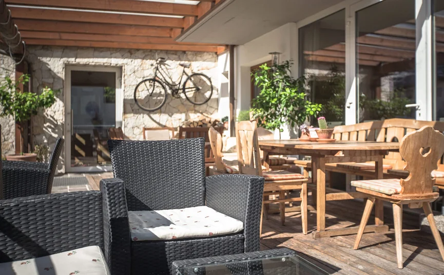 Terrace with black seating, wooden table, and bicycle mounted on wall