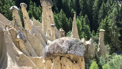Earth pyramids topped with large stones in a forest