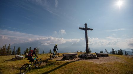 Bike & Taste die Salzburger Sportwelt © David Karg Zwei Mountainbiker am Gipfelkreuz bei sonnigem Bergwetter
