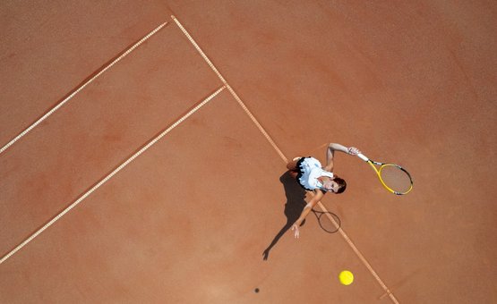 Short Game am Brennsee Frau spielt Tennis und schlägt den Ball auf einem Sandplatz von oben gesehen